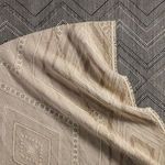 Taupe and cream Suriya rug folded on top of a black and white zigzag patterned rug