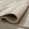 Rug folded to highlight thickness and weave details in beige tones