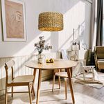 Pendant light hanging above round dining table with wooden chairs in bright room setting