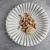 White marble ruffled bowl shown from above with natural potpourri inside on gray textured surface