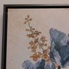 Close-up of painting corner showing delicate brownish-orange stems against parchment background with black frame