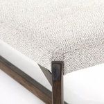 Close-up of the corner where the fabric seat is tightly wrapped around the dark wood bench frame