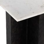 Close-up of marble tabletop corner resting on textured black metal legs