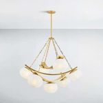 Duxbury Chandelier lit with smooth opaque white glass shades and gold curved metal bands against white ceiling