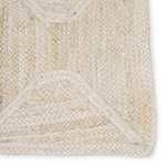 Close-up on braided edges and texture of natural fiber rug highlighting ivory and beige tones and detailed weave