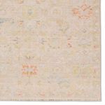 Detailed close-up of rug’s floral motifs and faded traditional pattern near an edge with fringe