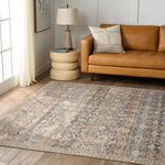 Rug styled in living room under natural light beside a tan leather sofa, beige side table, and tall lamp