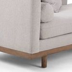 Close-up of chaise walnut wood leg and base corner beneath the left arm fabric upholstery