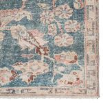 Close-up of rug corner showing worn texture and detailed floral patterns in teal and rust tones
