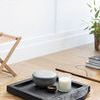 Tray styled on wooden coffee table with candle, ceramic bowl, and natural light background