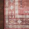 Close-up of rug’s patterned border area with warm tones against dark hardwood flooring