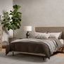 styled bedroom scene with Carly 5d Dresser, bed, nightstand, soft textured rug, and large plant