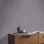 Wallpaper shown applied on wall behind wooden furniture with books and plants, highlighting scale and room context