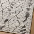 Close diagonal view of rug on hardwood with visible intersecting linear and diamond charcoal motifs