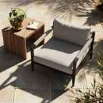 Sherwood chair on sunny stone patio next to small wooden side table with plant and book