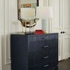 Florence dresser styled with books and lamp in traditional room setting with mirror and white paneled wall