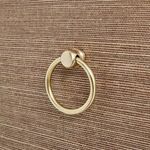 Close-up of golden metal ring pull on drawer with textured earthy brown background