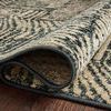 Folded rug corner showcasing the low pile and tightly woven construction on a hardwood floor