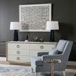 Ansel cabinet in dark room setting with patterned armchair, blue lamps, and neutral art piece on wall