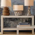 Styled console table with artful lamps and books paired with matching bench nearby