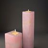Two pink alabaster T-Lite holders lit with tealight candles against dark background