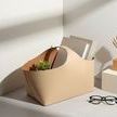 Napa bucket styled as decor holding books and a plant, shown in bright corner with shadows and eyeglasses nearby
