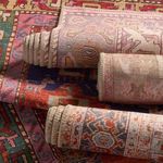 Stack of rolled vintage style rugs showing varied patterns and soft woven edges