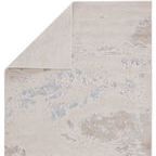 Back side of the rug folded over, showing solid light gray backing contrasting the abstract pattern.