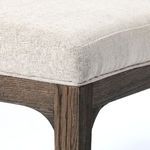 Close-up showing textured beige fabric tightly wrapped on seat cushion with visible seams