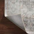 Rug corner folded back revealing backing material and neat edging stitching