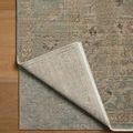 Corner of Briar Sky Grove rug lifted to expose light-colored woven backing and floor underneath