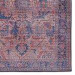 Zoomed in shot of rug corner highlighting intricate border design in deep blue and pink