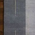 Rug corner on wooden floor emphasizing color contrast and weave detail in slate and natural hues