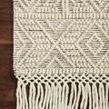 Close-up of Noelle Ivory / Black Rug fringe and geometric texture on dark hardwood floor