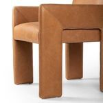 Slightly blurred angled view of Amur Dining Armchair emphasizing overall form and tan leather