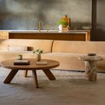 Living room scene showing Naomi sectional paired with round wooden and stone side tables in natural light