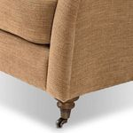Detail of front wooden leg and caster on Lynne chair with fabric stretched tightly
