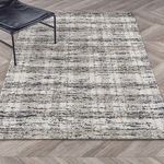 Full rug laid flat on chevron-patterned wood floor with chair leg partially on rug