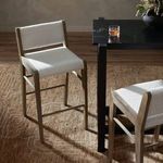 Two Charon white boucle counter stools styled at a black bar-height table on a brown patterned rug in natural light