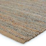 Close-up corner showing thick woven texture and braided edge of beige and gray fibers