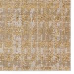 Detailed view of rug corner highlighting geometric design and soft sheen in gold and taupe