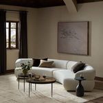 Sectional sofa styled in a living room with neutral walls, area rug, and layered coffee tables
