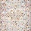 Vintage style rug with intricate symmetrical floral and geometric patterns in grey, ivory, and rust tones