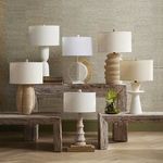 Linz Table Lamp styled among six other lamps on rustic wood benches against grasscloth wallpaper