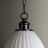 Close-up of pendant light’s dark bronze metal ring and chain connection above fluted glass shade