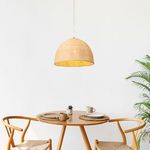 Pendant light hanging above wood dining table set with two chairs and green plant nearby