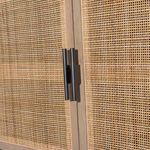 Close-up of black iron hardware handles on woven cane sideboard doors