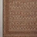 Overhead close-up of rust Fiesta rug corner laying flat on smooth floor surface.