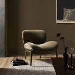 Chair styled in warm-toned room setting on patterned rug with minimal decorative objects
