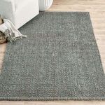 Annello jute rug styled under light-colored sofa on natural wood floor